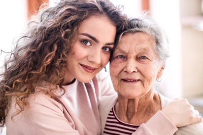 girl with grandmother hugging at home