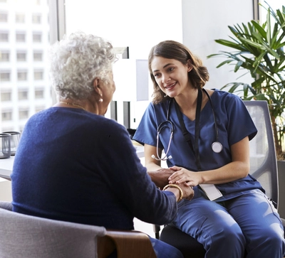 Nurse wearing scrubs talking to an elderly person.